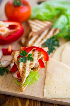 fried toast with chicken, salad, greens on a wooden table .