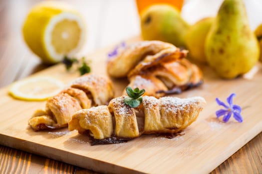 Sweet pastries, puff pastries with pears, on a wooden table .