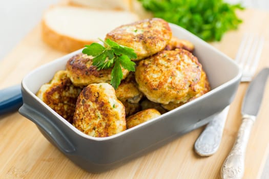 fried meat cutlets in a ceramic form on a wooden table .