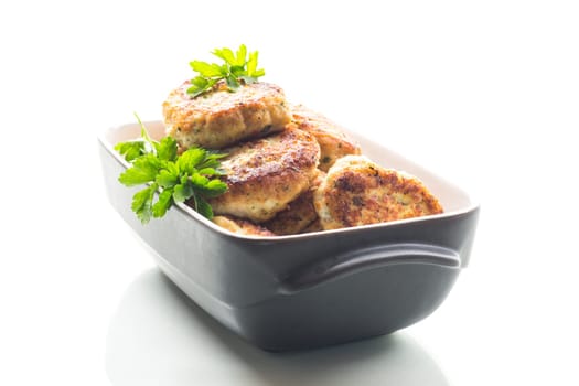 fried meat cutlets in a ceramic form on a wooden table .