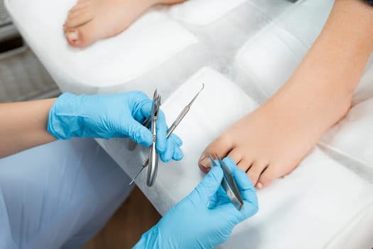 Top view of professional medical pedicure using special nail instruments in the clinic by podologist.