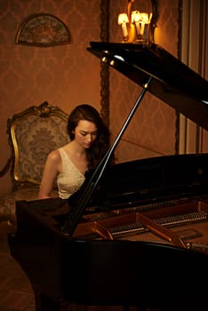 Mansion, woman and paying with musician, lounge and pianist in a ballroom with luxury instrument. Entertainment, palace and vintage fashion of sound artist with song and manor with glamour and style.