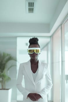 Portrait of one beautiful African businesswoman in a white suit with virtual reality glasses standing in the office, close-up side view.