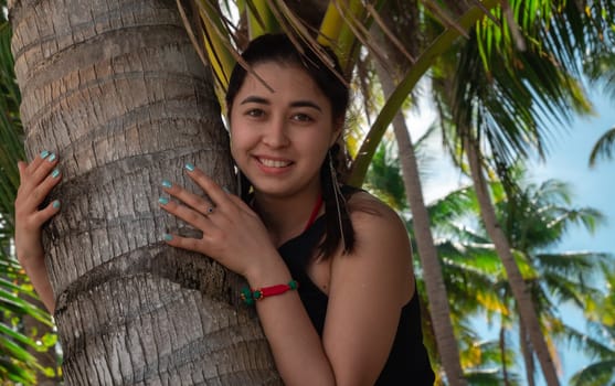 Close-up of cute asian girl hugging palm tree trunk, summer vacation, relaxation on the beach
