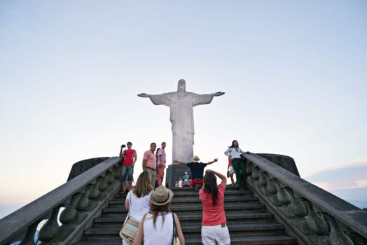 People, christ and steps with statue for tourism in rio de Janeiro of redeemer, sightseeing or landmark sculpture. Group, community or crowd on tour, trip or monument of iconic attraction in Brazil.