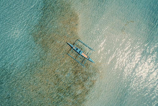 Aerial drone view of boat anchored in the bay with clear and turquoise water. Boat in the tropical lagoon. Tropical landscape.