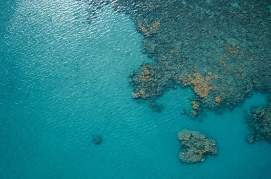 Aerial top view of the blue ocean and coral reef on sunny day. Sea surface.