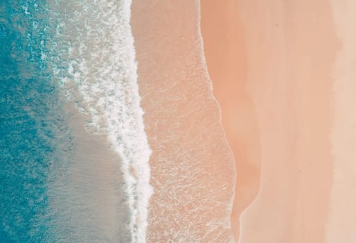 Aerial top view of turquoise ocean wave reaching the coastline.