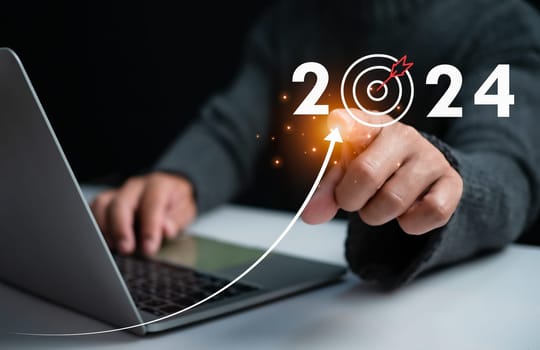 Businessman pointing at dart board icon Represents the goal setting for 2024, concept of startup, financial planning, development strategy, business goal setting.