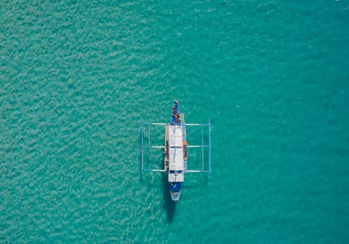 Aerial drone view of boat anchored in the bay with clear and turquoise water. Boat in the tropical lagoon. Tropical landscape.