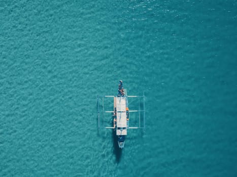 Aerial drone view of boat anchored in the bay with clear and turquoise water. Boat in the tropical lagoon. Tropical landscape.