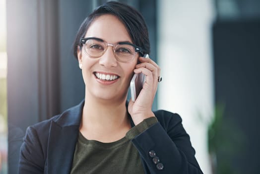Happy woman, portrait and business with phone call for friendly discussion by window at office. Female person or employee with smile on mobile smartphone for fun conversation or talking at workplace.