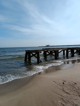 Wooden old broken pier in the baltic sea coast cold calm sea in winter day. High quality photo. Sea walk, seaside walk in a cold day