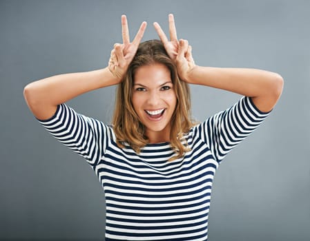 Woman, bunny ears and fingers in studio portrait, funny sign and play on gray background. Female person, emoji and rabbit icon or symbol for comedy, comic gesture and mockup space for easter humor.