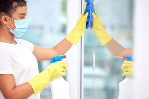 Girl, spray and cleaning window with detergent in lounge for safety or protection from disease or dirt. Female person, maintenance and disinfect glass for health or wellness from virus or bacteria.