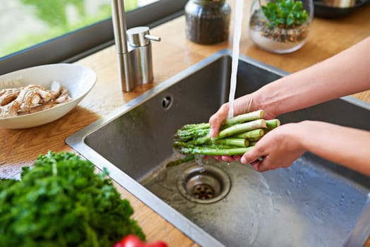 Cooking, hands and woman washing vegetables for meal prep, fresh and healthy food for lunch. Diet, wellness and person at kitchen sink with ingredients, nutrition and cleaning salad in water at home.