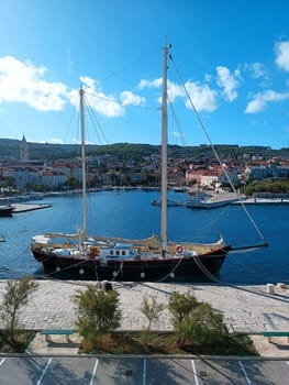 Brown wooden sailboat with lowered sails moored on the pier in Brac Split sunny day blue sea. High quality photo