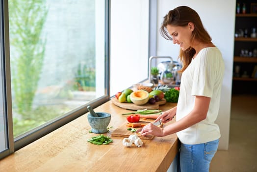 Cooking, home and happy woman with healthy food, meal prep and cutting fresh vegetables for lunch. Diet, wellness and girl at kitchen counter with ingredients, nutrition and dinner in apartment