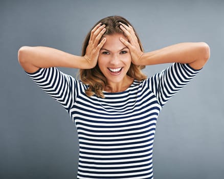 Model, portrait and covered ears with studio, excitement and celebration for winner. Woman, smile and happiness for good news, promotion and achievement with victory isolated on grey background.