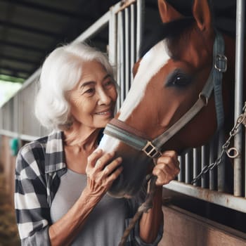 Portrait of elderly happy woman with petting a brown and white horse in a stable