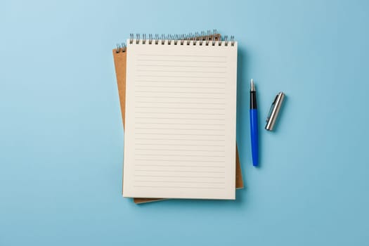 Top view of notebook and fountain pen on blue background