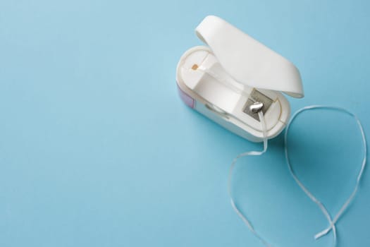 Top view of dental floss in white box on blue background