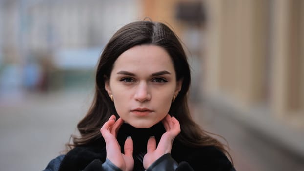 Sensitive portrait of a brunette girl on a cloudy spring day on a city street