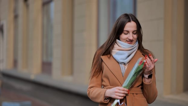 Portrait of a happy shade girl with a tulip in the background of the city in the cold season