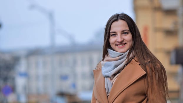 Beautiful young girl portrait in a coat in spring on a city street