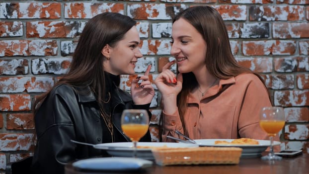 Two young girls gossiping sitting in a cafe