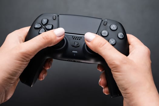 BERLIN , GERMANY - FEBRUARY 14 2024: Video game controller in womans hand on the black ground.