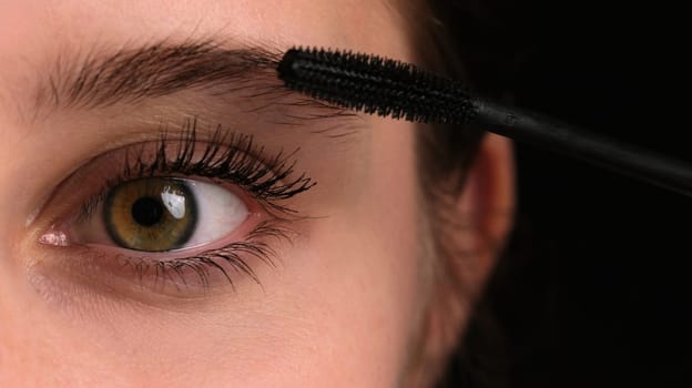 Girl Seen Up Close Applying Black Mascara To Her Long Eyelashes