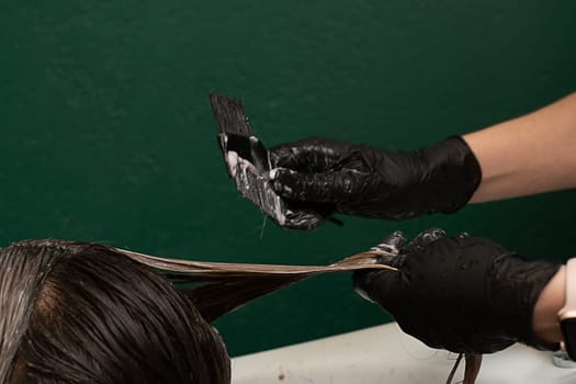 Beauty sphere. Hair coloring in a beauty salon. A master hairdresser-colorist combs long hair with a comb and brush and washes it with shampoo in a hair washer. Close-up. Business concept. No faces.