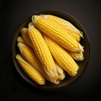 Bowl full of yellow corn cobs in green leaves. Corn as a dish of thanksgiving for the harvest, a picture on a black isolated background. An atmosphere of joy and celebration.
