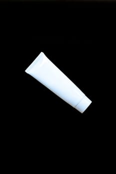 blank cosmetics tube. Plastic cream box isolated on black background.