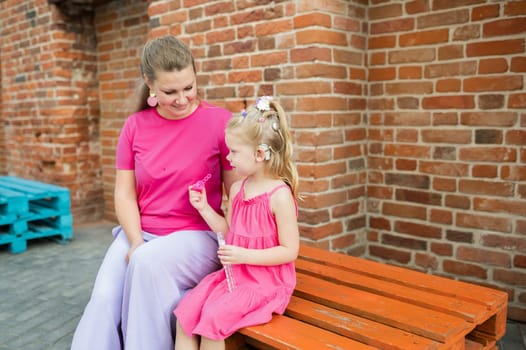 Blonde little girl with cochlear implant playing with her mother outdoor. Hear impairment deaf and health concept. Diversity and inclusion. Copy space.