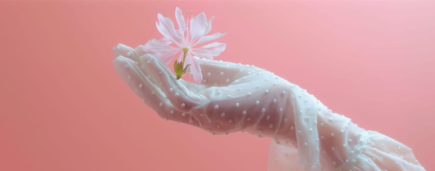 Delicate pink flower on a white dotted glove against a pink background