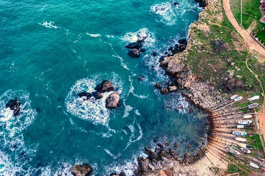 Aerial top view of the small rocky bay and pier with fishing boats on the shore