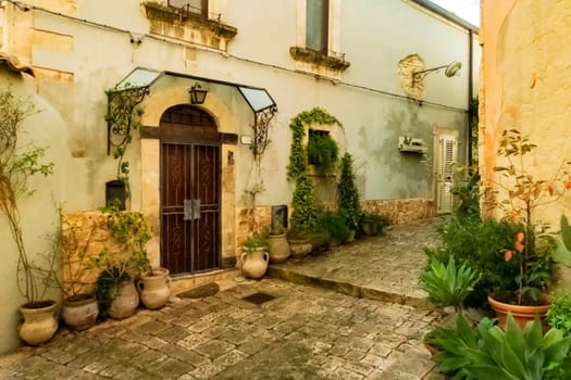 Small stone street with flowers in the Ragusa Ibla city in Sicily, Italy