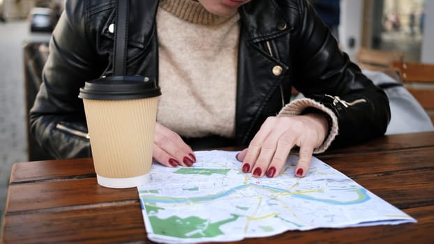 Stylish Female Tourist Checks City Sightseeing Route On Map While Sipping Coffee In Street Cafe