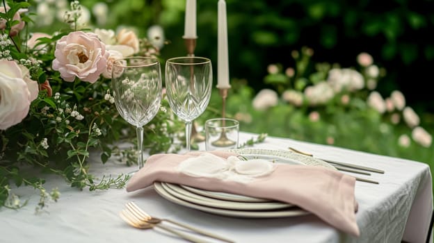 Table setting with rose flowers and candles for an event party or wedding reception in the summer garden.