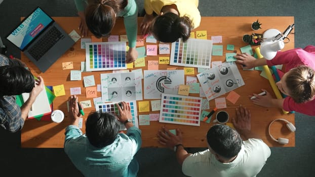 Top view of business team write graphic logo on meeting table with colorful sticky notes and design while explain idea. Project manager sharing idea and explain concept art to smart team. Symposium.