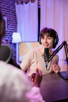 Happy women meeting in studio to record podcast show with professional sound equipment. Vlogger and guest broadcasting live chat to create comedic internet channel content together