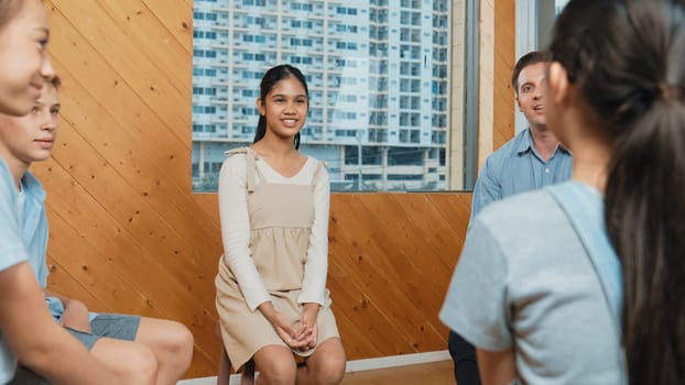 Young student smiling while listening other student in meeting or group discussion. Cute teenager talking about her experience and sharing to friends in mixed races. Creative education. Edification.