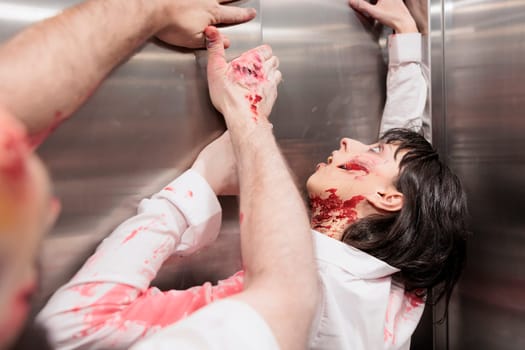 Walking dead creatures stuck in office elevator, trying to escape to infect more people and eat brains. Terrifying bloody cadavers trapped in escalator, pulling on metallic doors