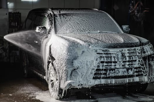 Man applying foam to black car in car wash