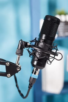 Professional black microphone for internet channel audio podcast live streaming. Mic equipment close up for sound and communication recording on radio in modern empty studio