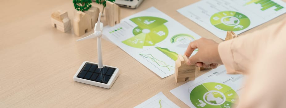 Environmental documents and a windmill model representing the use of clean energy are scattered on the table during a green business discussion about investing in clean energy. Closeup. Delineation.