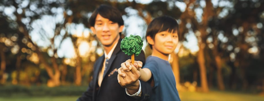 Asian boy and businessman holding paper tree together as Earth day concept as corporate social responsible to make greener environmental protection for sustainable future generation. Panorama. Gyre