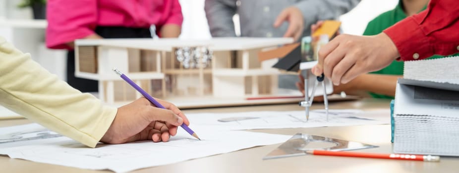 Professional architect team select sustainable house materials while skilled engineer using divider measure blueprint with house model and color palette placed on meeting table. Closeup. Variegated.